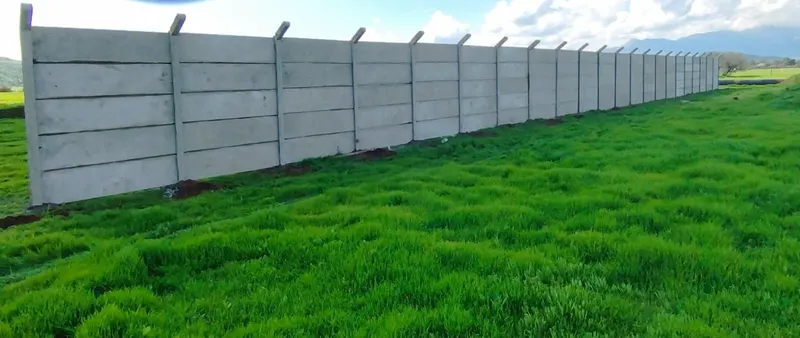 Cierre perimetral largo con pilares pasados en un terreno de pasto